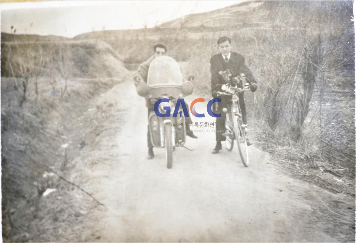 오토바이가 처음 나올 무렵 오토바이와 자전거를 타고 친구와 외내 마을로 들어서는 동생 금준섭 작은그림